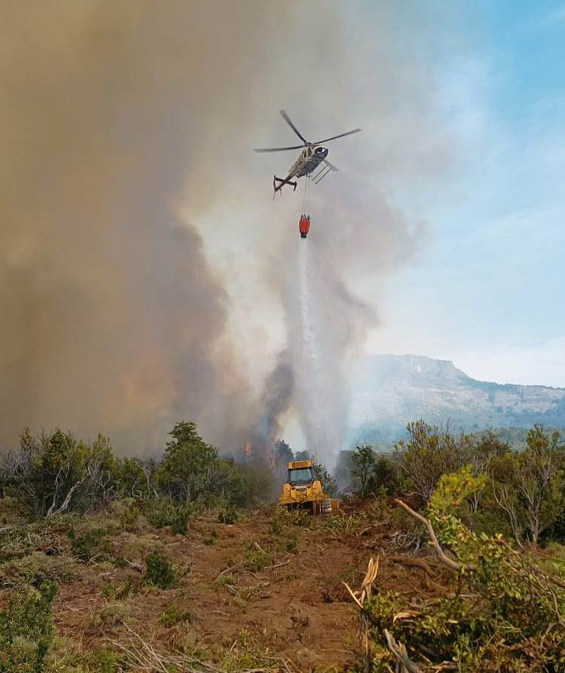Tres helicópteros con helibalde combaten el fuego desde el aire.