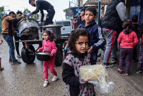 Niños palestinos desplazados llevan raciones de sopa de lentejas rojas, distribuidas por voluntarios en Rafah, en el sur de la Franja de Gaza.
