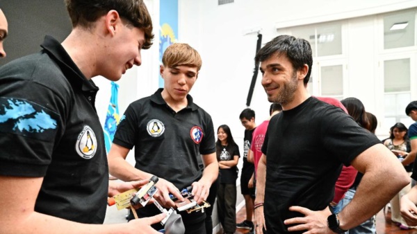 Torres conversando con dos estudiantes que participaron de la Liga de Robótica. la 