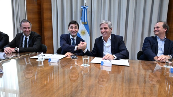Torres y Caputo sellan el acuerdo con un apretón y sonrisas. Adorni y Daniel González, de Energía, acompañan.