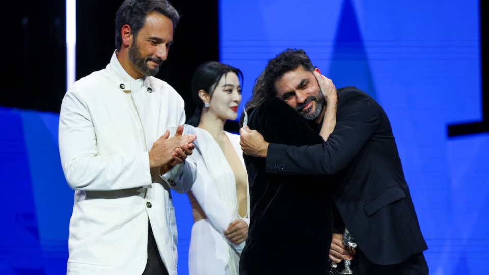 El director brasileño Gabriel Mascaro sostiene el Oso de Plata del Gran Premio del Jurado por "O ultimo azul" mientras se abraza con Denise Weinberg y Rodrigo Santoro aplaude durante la ceremonia de entrega de premios de la 75ª Berlinale.