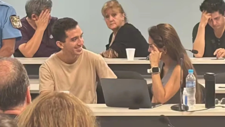 El imputado Néstor Soto esbozando una sonrisa mientras conversa con su abogada, durante un cuarto intermedio.