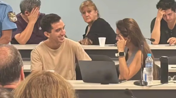 El imputado Néstor Soto esbozando una sonrisa mientras conversa con su abogada, durante un cuarto intermedio.