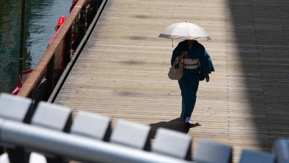 Una mujer utiliza un paraguas como parasol, pero ¿quién para el Cambio Climático?