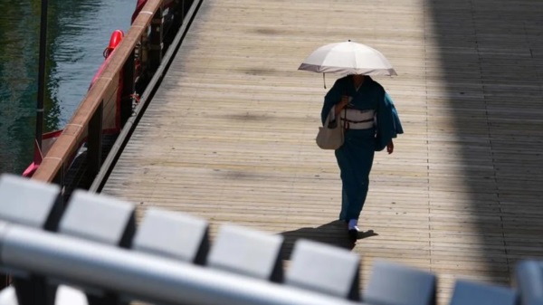 Una mujer utiliza un paraguas como parasol, pero ¿quién para el Cambio Climático?