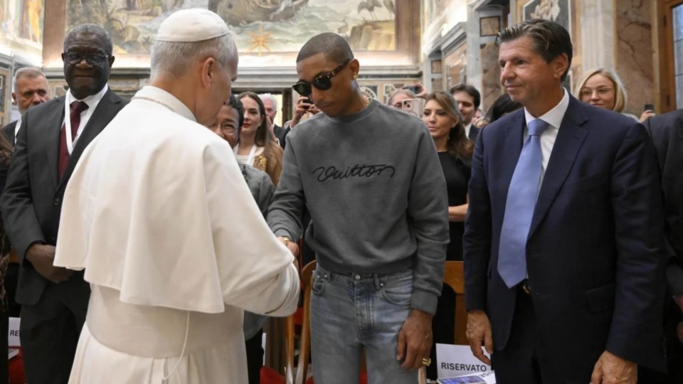 El músico Parrel Willims saluda al Papa León a su  llegada al Vaticano.