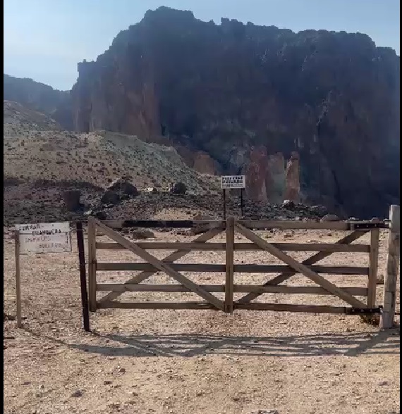 Una tranquera con candado sobre un camino público.