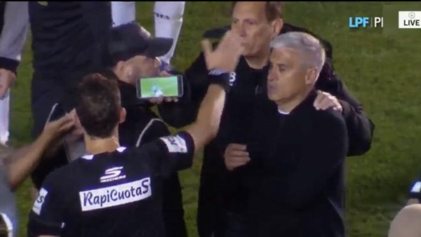 El cuerpo técnico del All Boys saca un celular para mostrárselo al árbitro y demostrar que no fue penal.