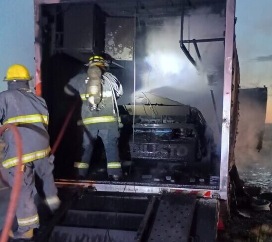 Bomberos trabajan sobre el tráiler. Adentro, el Mustang totalmente quemado.
