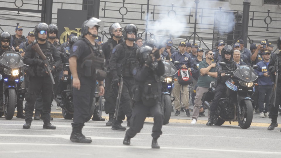 Un policía lanzando un gas lacrimógeno.