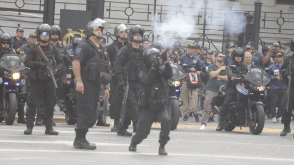 Un policía lanzando un gas lacrimógeno.