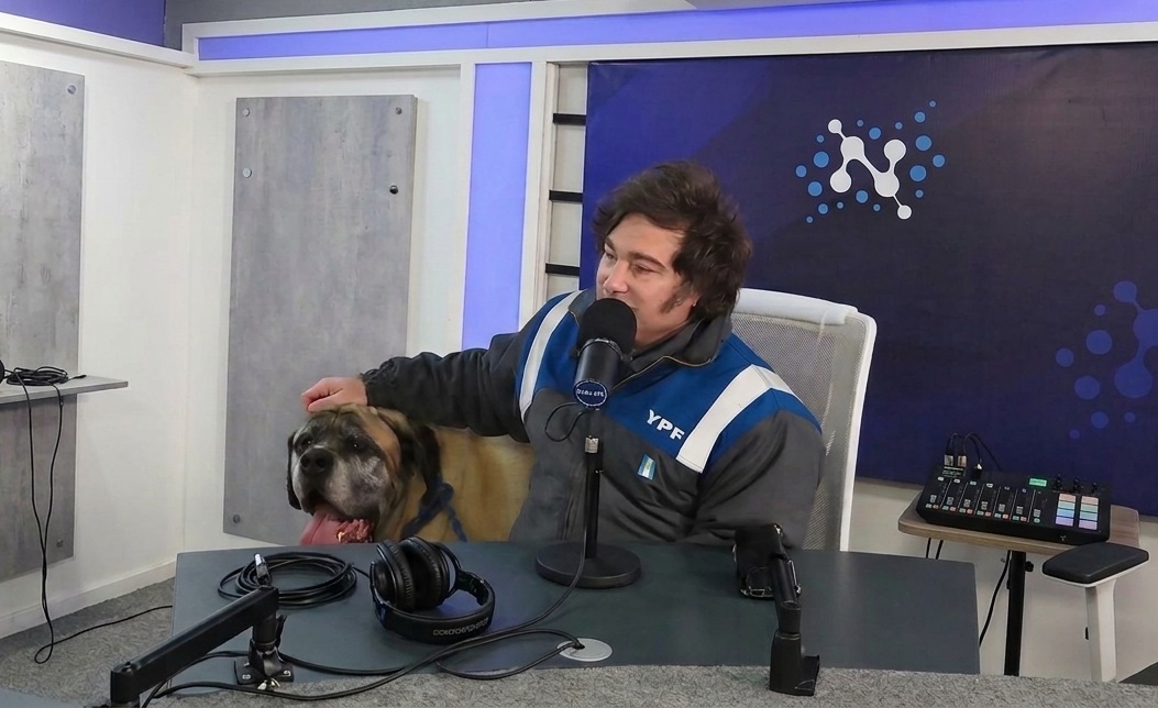 Milei en un streaming amigable, junto a uno de sus "hijos de cuatro patas" y el mameluco de YPF.