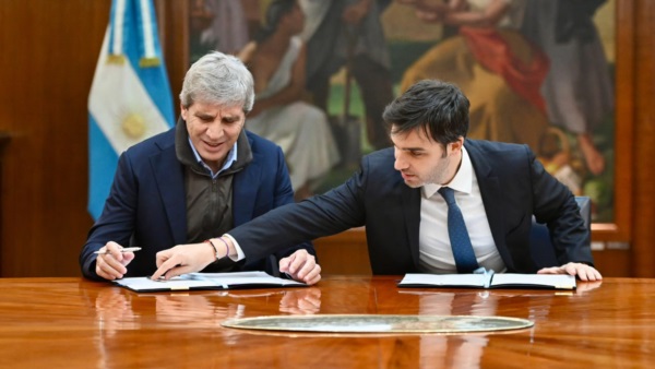 Torres parece indicarle algo a Caputo en la firma del cancelación del REOR.